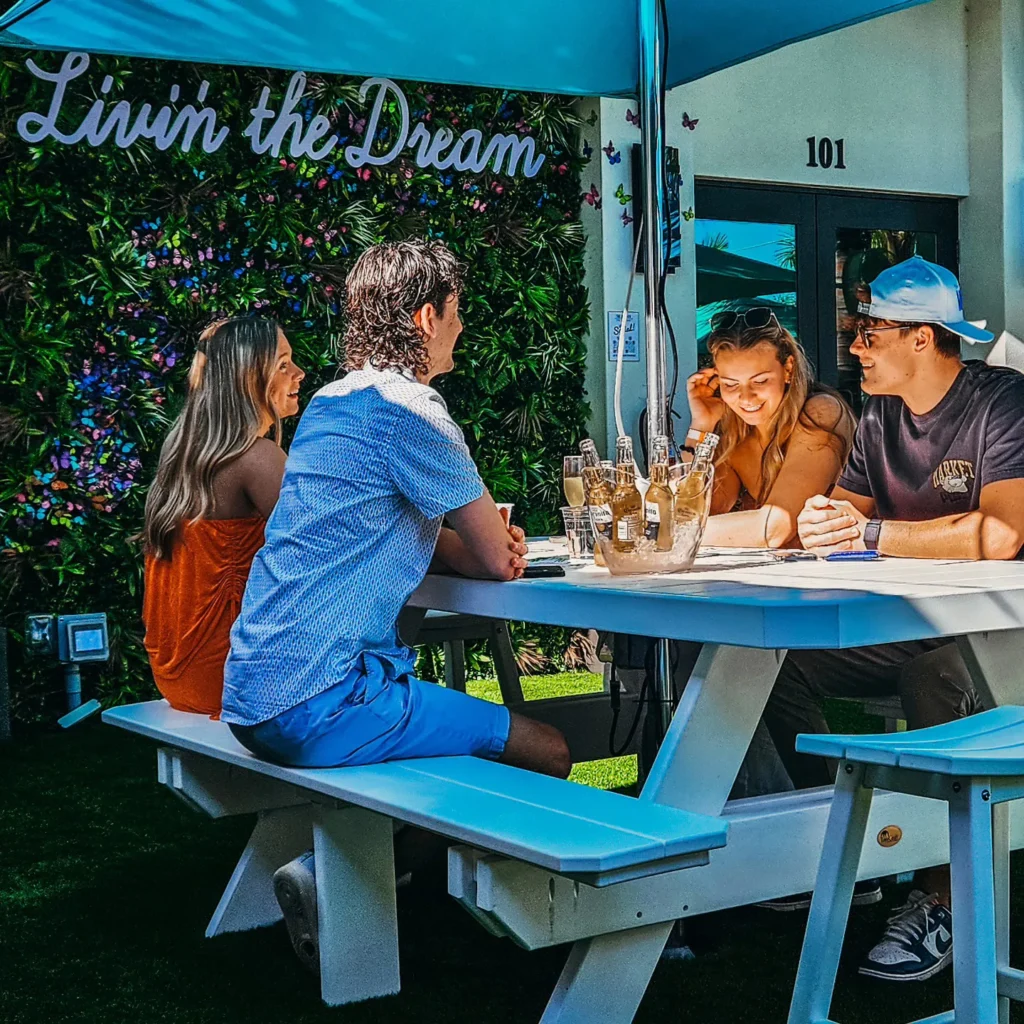 Four young people sitting at a table outside at The Kitchen and The Mini Bar in Naples, FL.